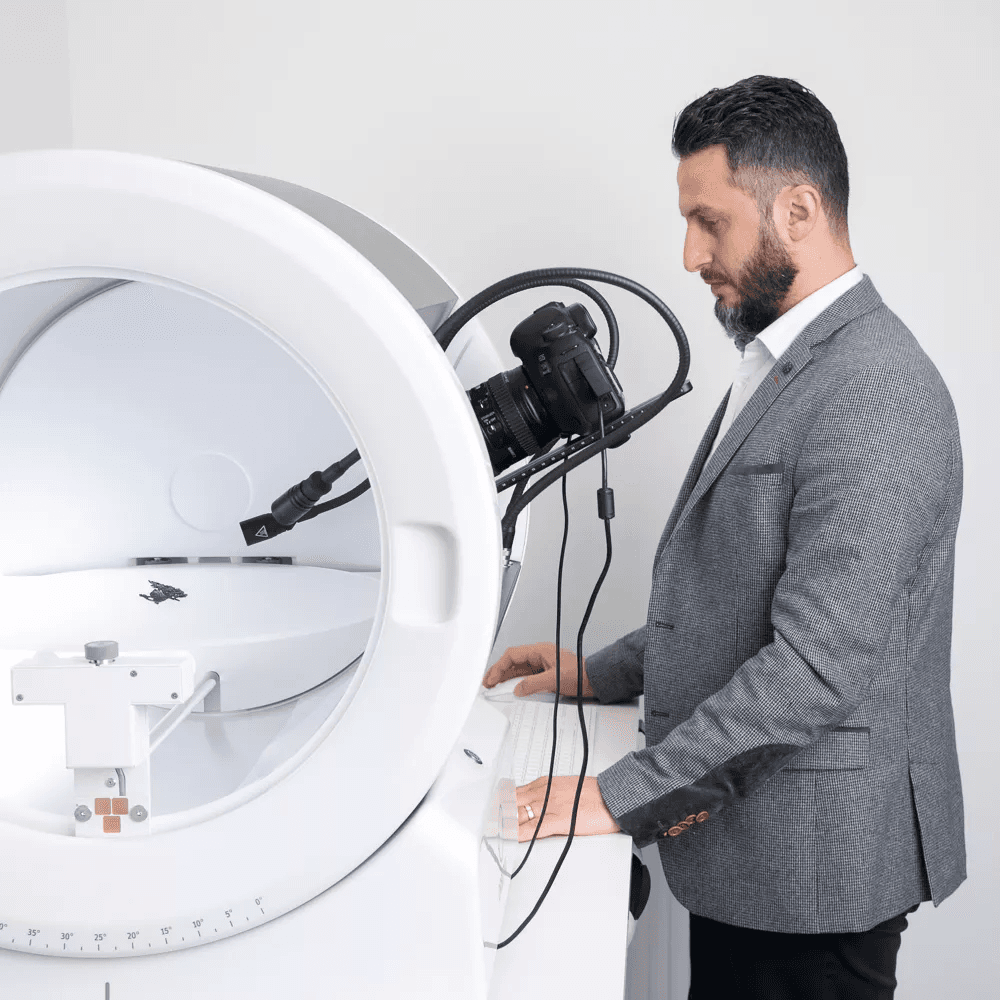 Man in a suit operating an Orbitvu photography device