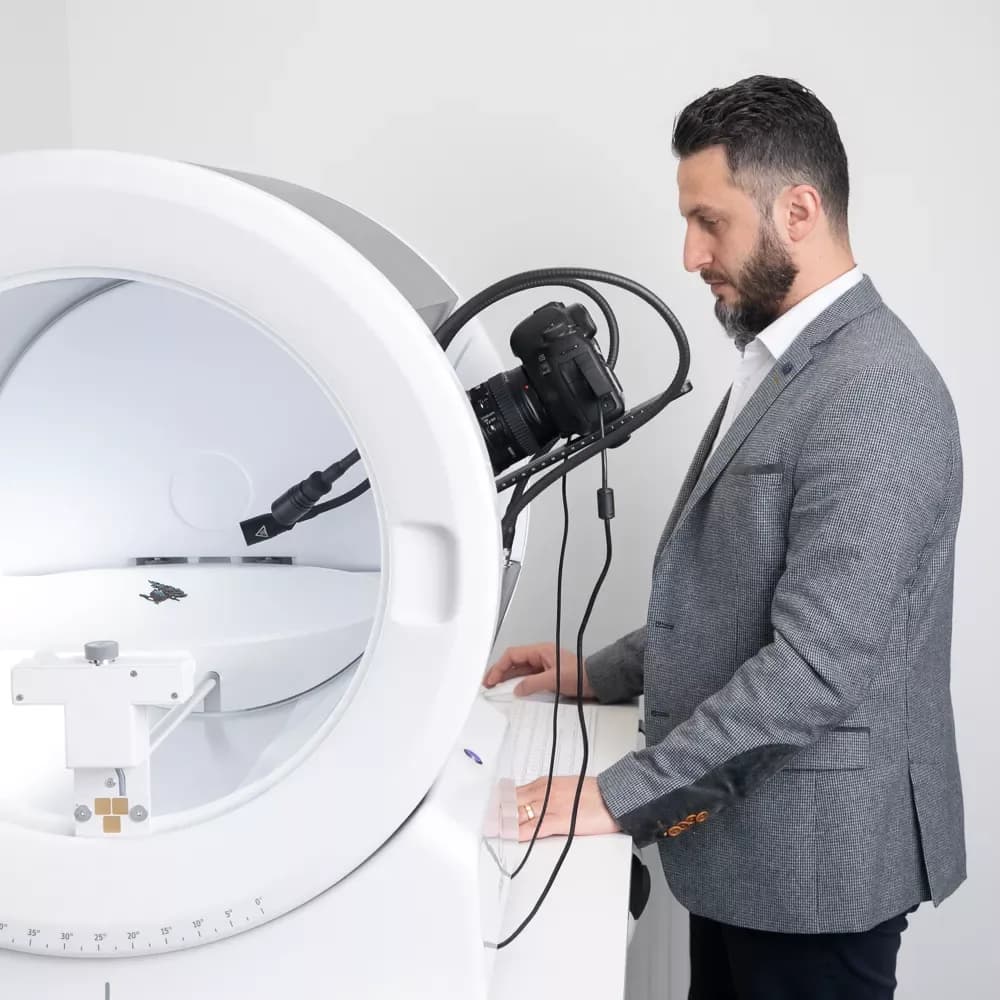 Man in a suit operating an Orbitvu photography device