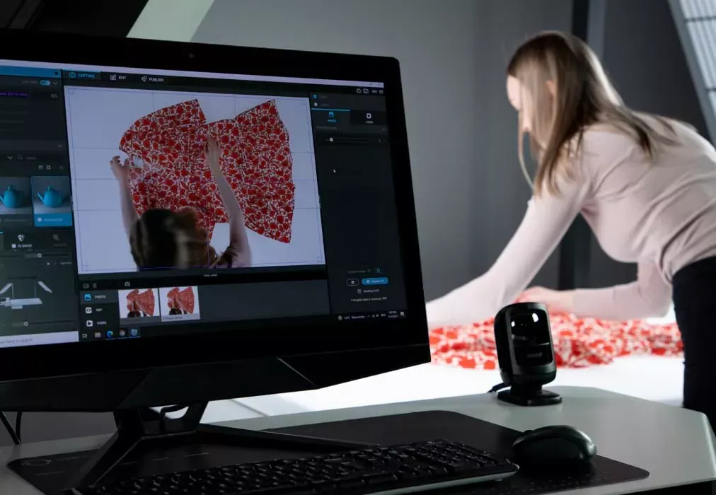 Photographer adjusting floral fabric garment with live view on monitor