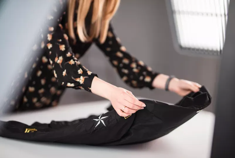 Product Stylist Arranging Black Jacket with Star Patch