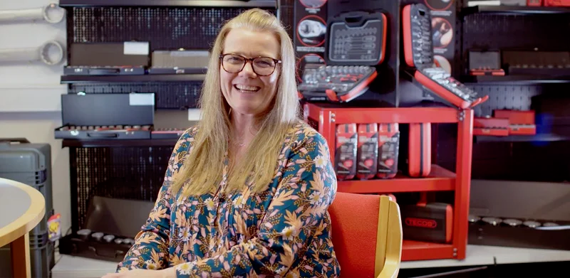 Smiling Woman with Glasses in a Tool Shop