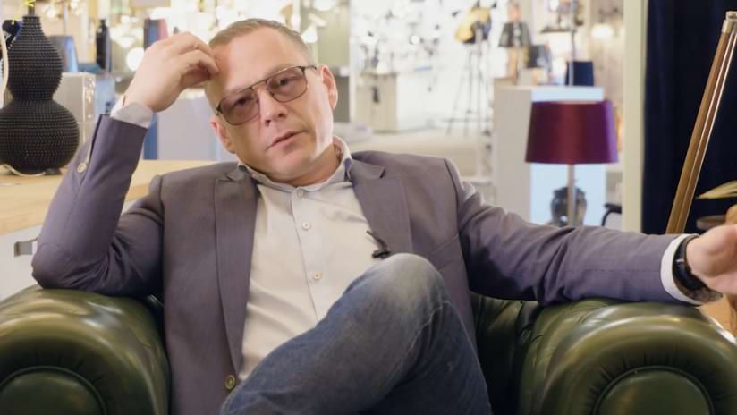 Middle-Aged Man in Blazer and Glasses Sitting in Green Leather Armchair