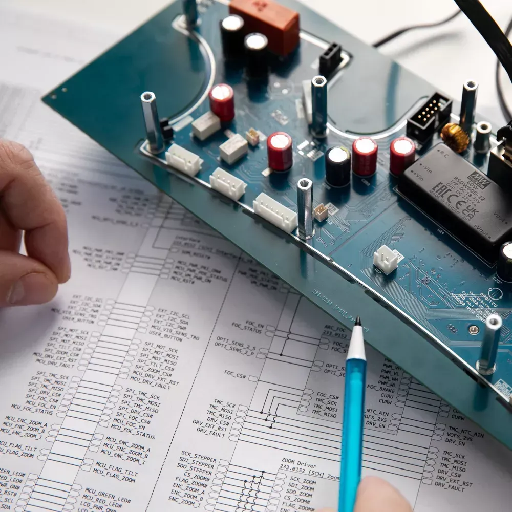 Engineer Reviewing Electronic Circuit Board and Schematic Diagram