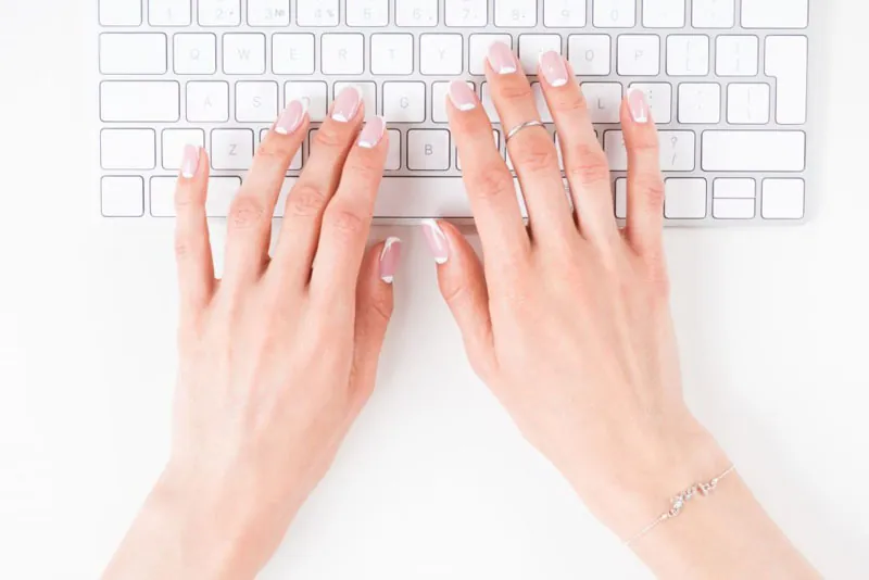 Hands typing on a white keyboard