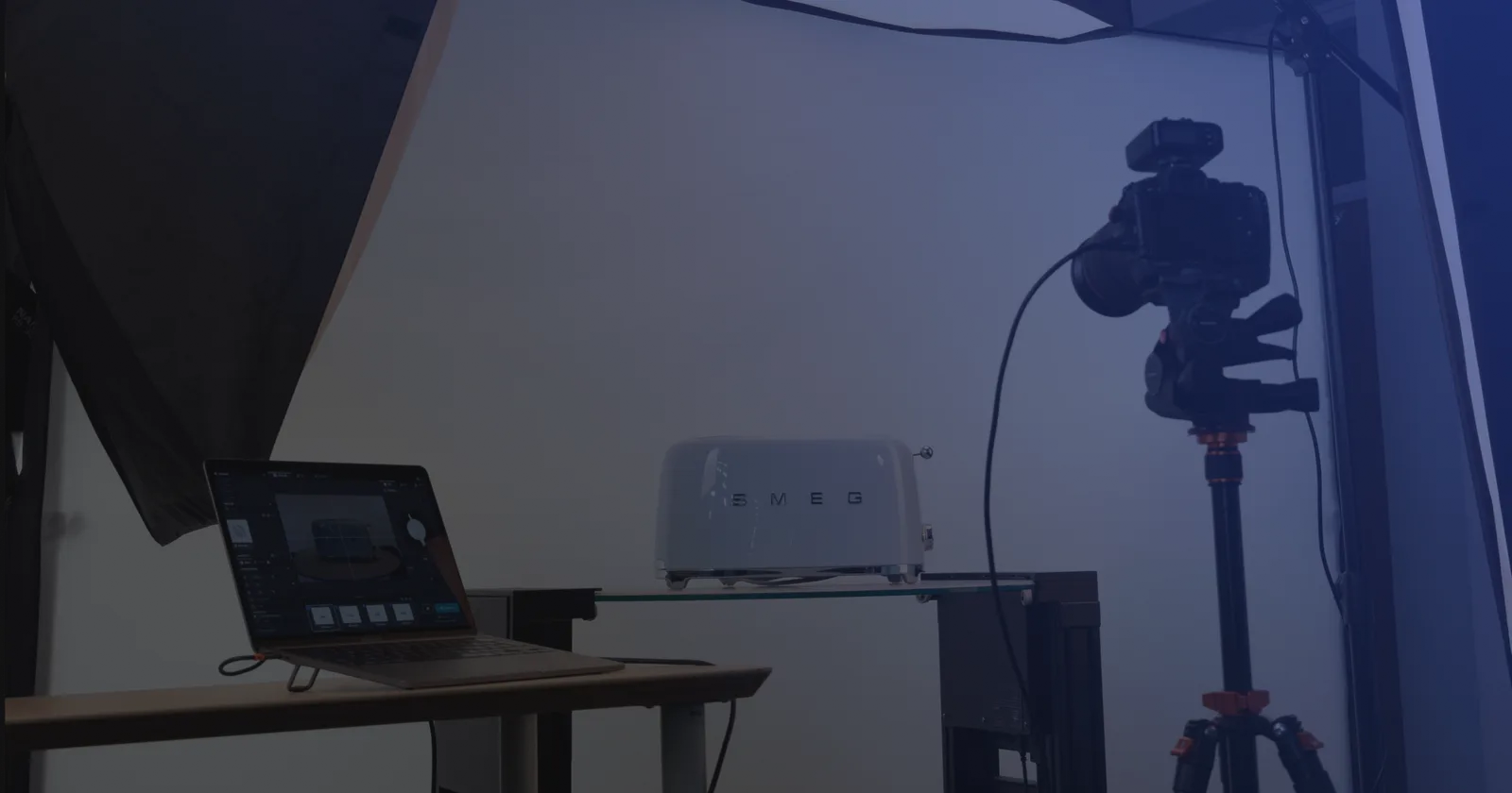 Tethered product photography setup - a laptop running capture software next to a camera on a tripod and a product on a glass shelf