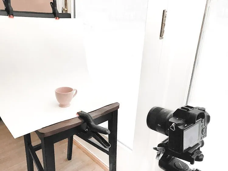 Natural light product photography set-up with a cup on a white sweep next to a window