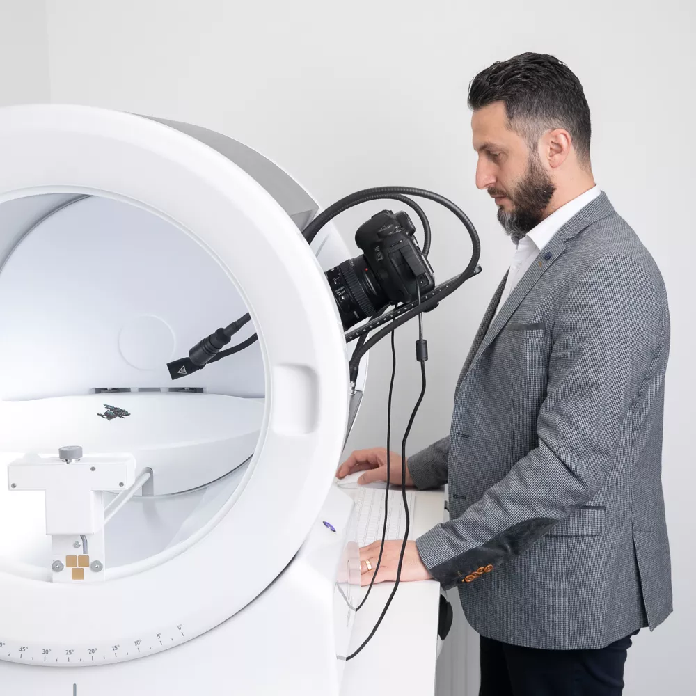 Man in a suit operating an Orbitvu photography device