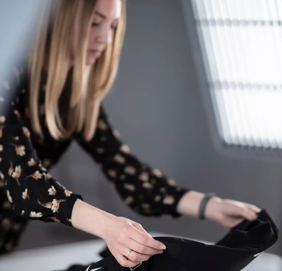 Product stylist arranging black garment for flat lay shoot