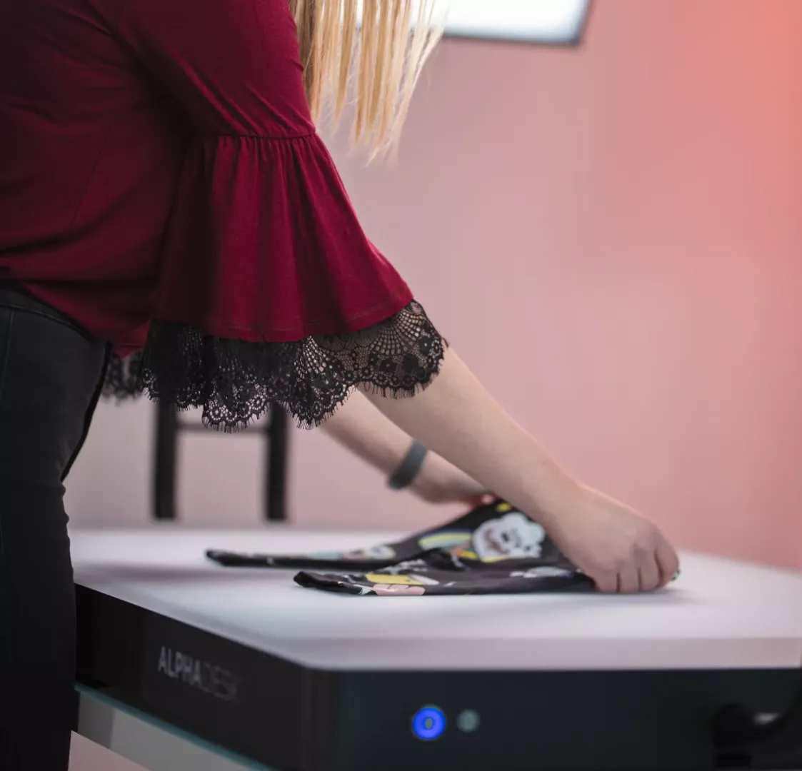 Woman folding children's clothing on a white desk with Alphadesk